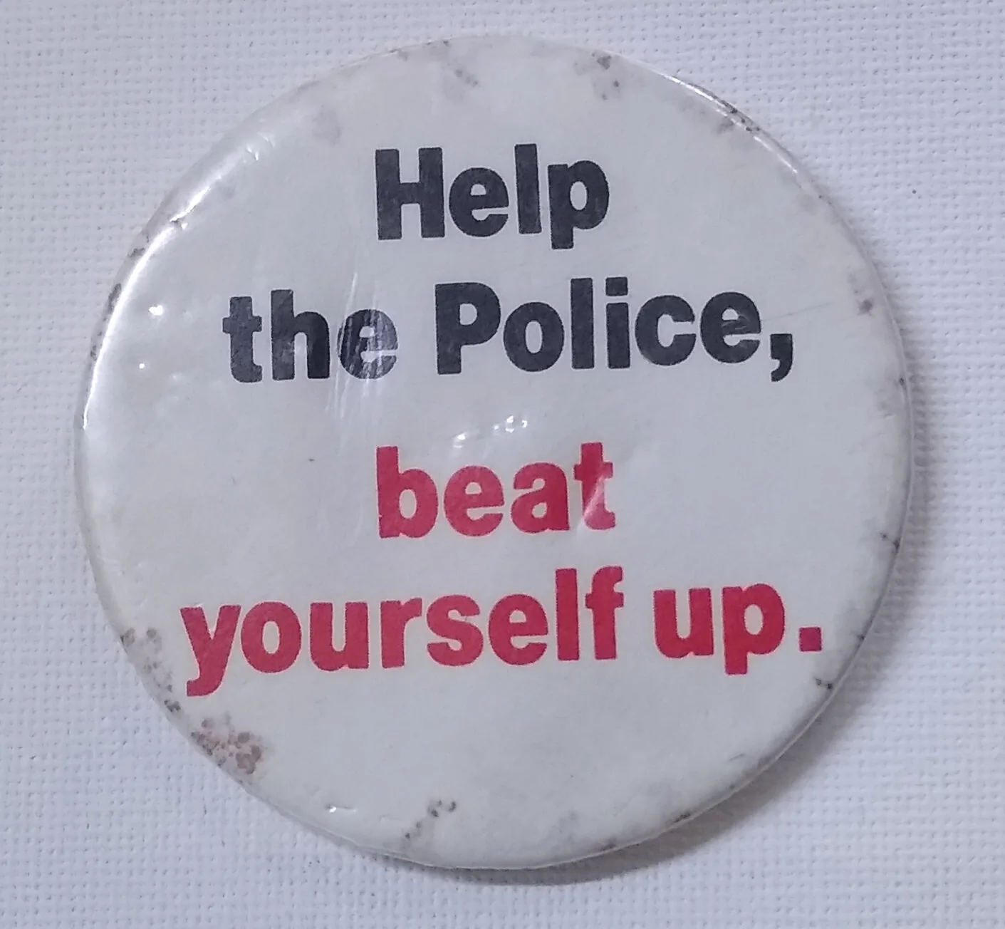 A pin reading "Help the Police, beat yourself up." on display at the Irish Republican History Museum in Belfast, Northern Ireland.